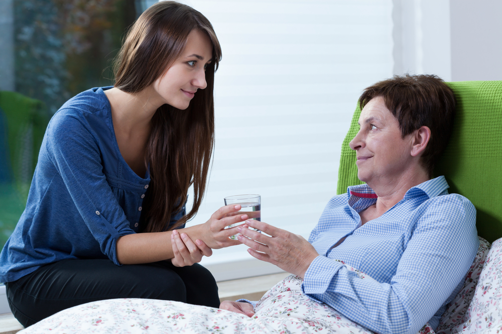 Young pretty girl giving the sick woman glass of water